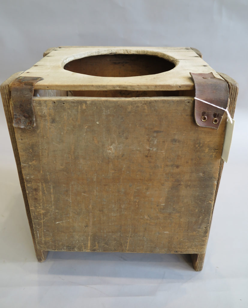 A rectangular timber box with a circular hole cut out of the top with a hinged lid to cover the hole when not in use.